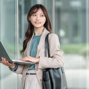 ノートPCを使いながら歩く女子大生