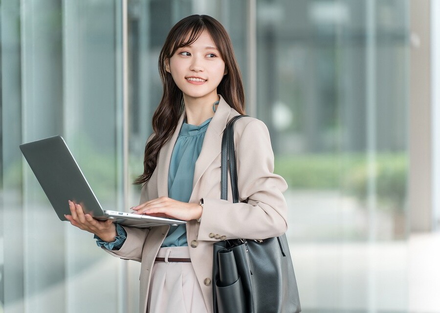 ノートPCを使いながら歩く女子大生